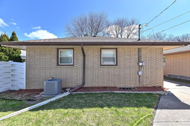 view of home's exterior with fence, a yard, central air condition unit, and brick siding