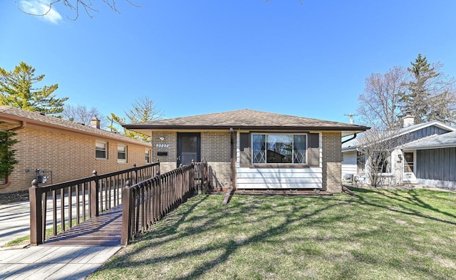rear view of property with fence, roof with shingles, a yard, and brick siding