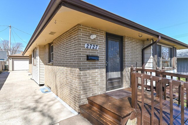 view of exterior entry with a wooden deck and brick siding
