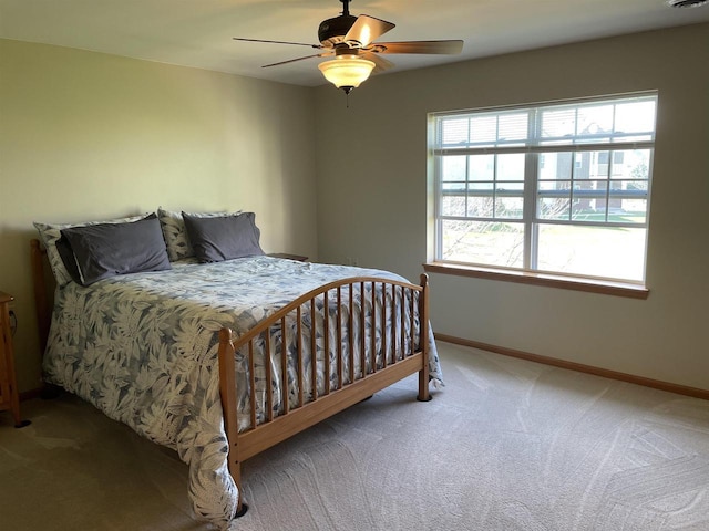 carpeted bedroom with ceiling fan and baseboards