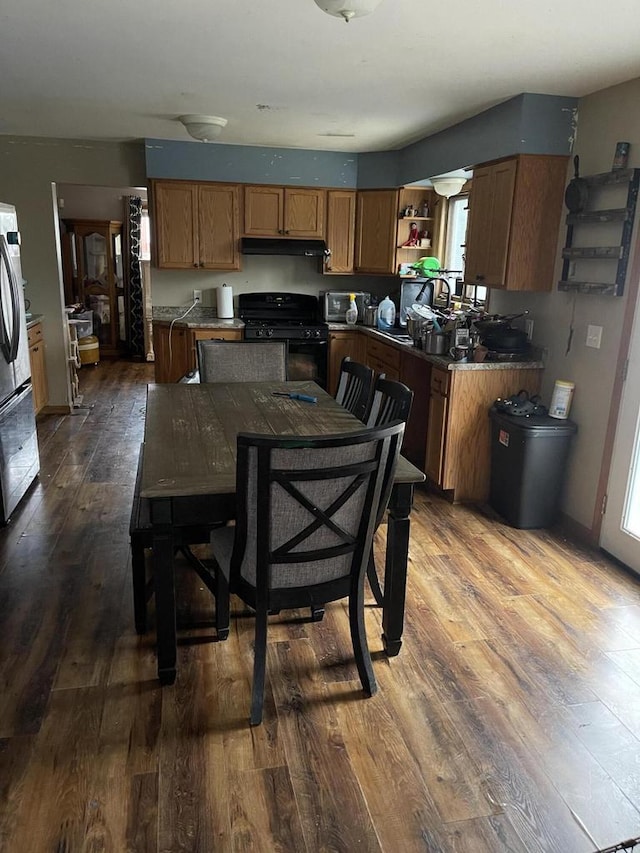 4327 29th St, Kenosha, WI 53144 - kitchen with black gas range, stainless steel refrigerator, dark wood finished floors, under cabinet range hood, and healthy amount of natural light