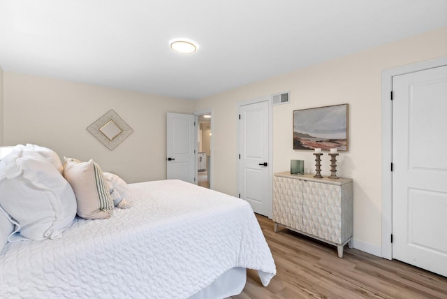 bedroom featuring visible vents, light wood-style flooring, and baseboards