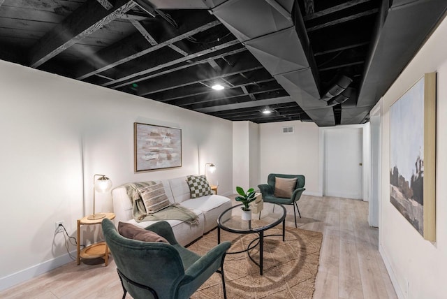 living area featuring baseboards, visible vents, and wood finished floors