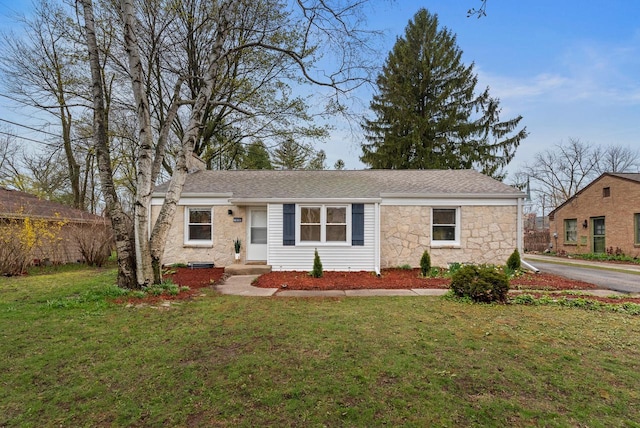 ranch-style house featuring a front lawn, roof with shingles, and stone siding