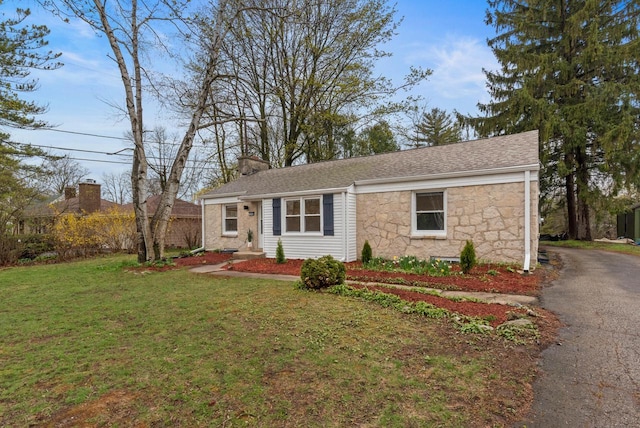 single story home with a front lawn, aphalt driveway, stone siding, and a chimney