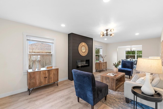 living area featuring a fireplace, baseboards, a chandelier, recessed lighting, and light wood-style flooring