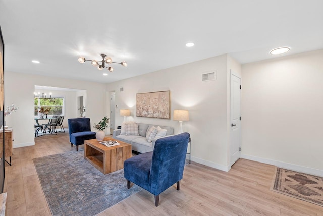 living area featuring visible vents, light wood-style floors, baseboards, recessed lighting, and a chandelier