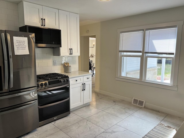 kitchen with appliances with stainless steel finishes, light countertops, white cabinetry, tasteful backsplash, and visible vents