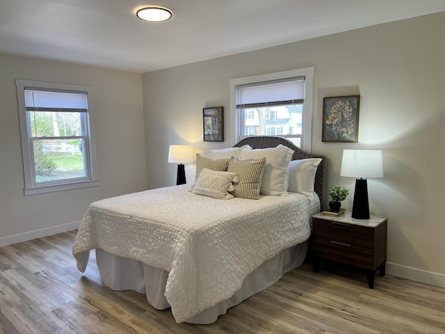 bedroom featuring baseboards, light wood-style flooring, and multiple windows