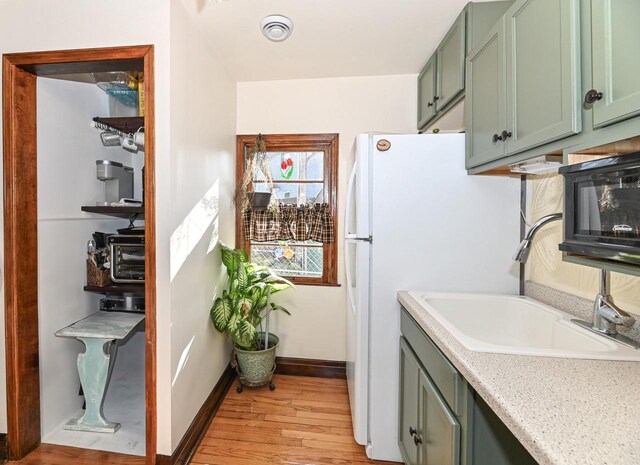 4308 W Dr, Delavan, WI 53115 - kitchen featuring a sink, light wood-style floors, green cabinets, visible vents, and light countertops