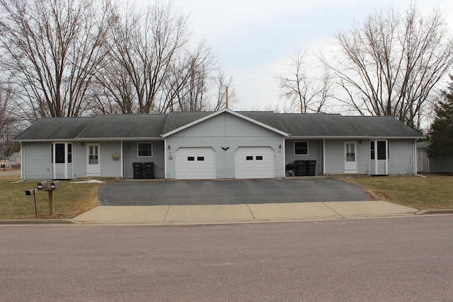 ranch-style home featuring driveway, a front yard, and an attached garage