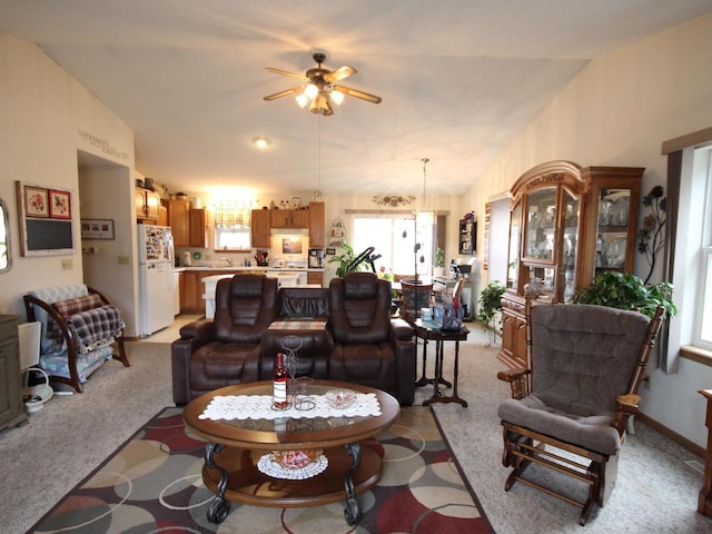 living area with ceiling fan, lofted ceiling, light colored carpet, and plenty of natural light