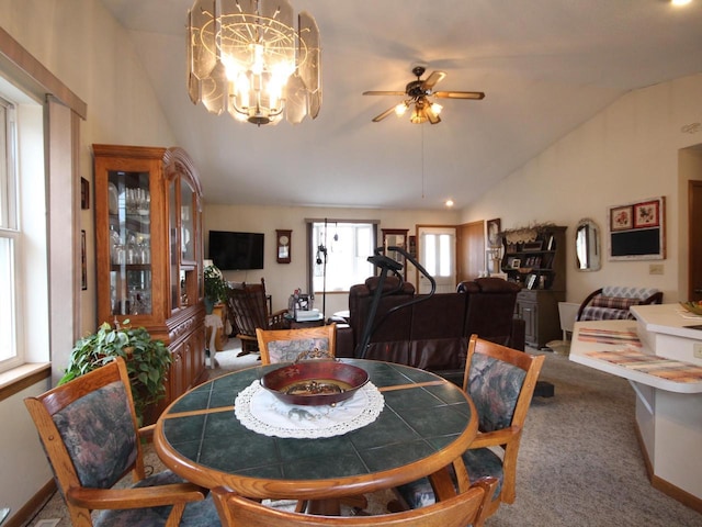 carpeted dining area with baseboards, ceiling fan with notable chandelier, and vaulted ceiling