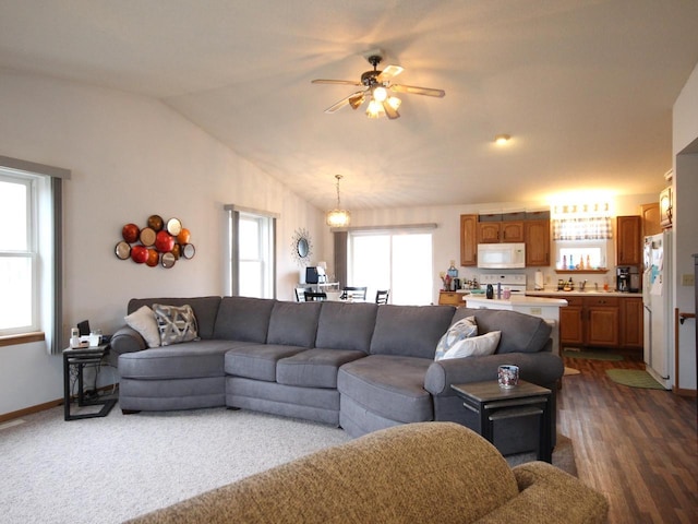 living area featuring baseboards, a ceiling fan, dark wood-type flooring, and vaulted ceiling