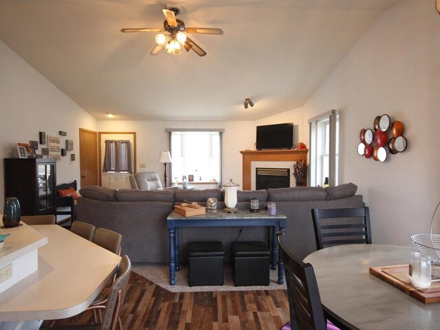 living area featuring a fireplace, a ceiling fan, vaulted ceiling, and dark wood finished floors