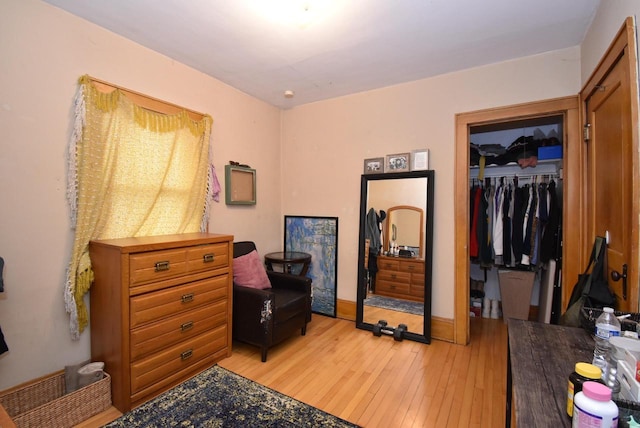 bedroom with baseboards, a spacious closet, light wood finished floors, and a closet