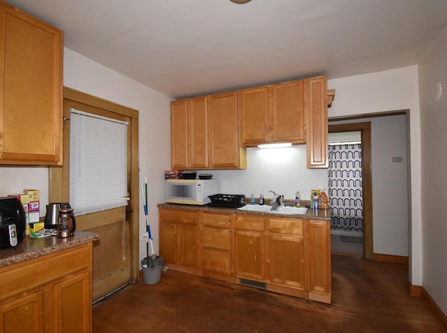 kitchen with visible vents, dark countertops, a sink, baseboards, and white microwave