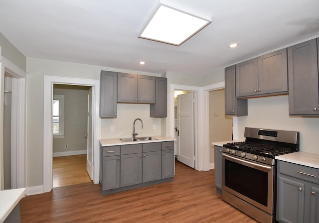 kitchen featuring a sink, light countertops, gray cabinets, and gas range