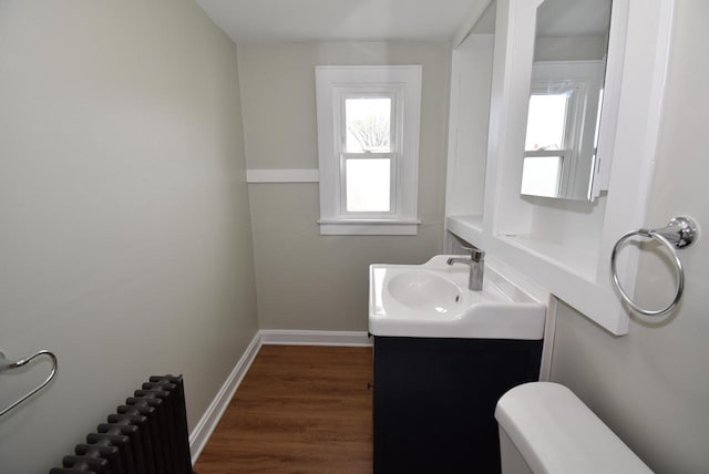 bathroom featuring vanity, radiator, wood finished floors, toilet, and baseboards