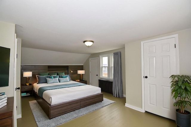 bedroom featuring baseboards, wood finished floors, and lofted ceiling