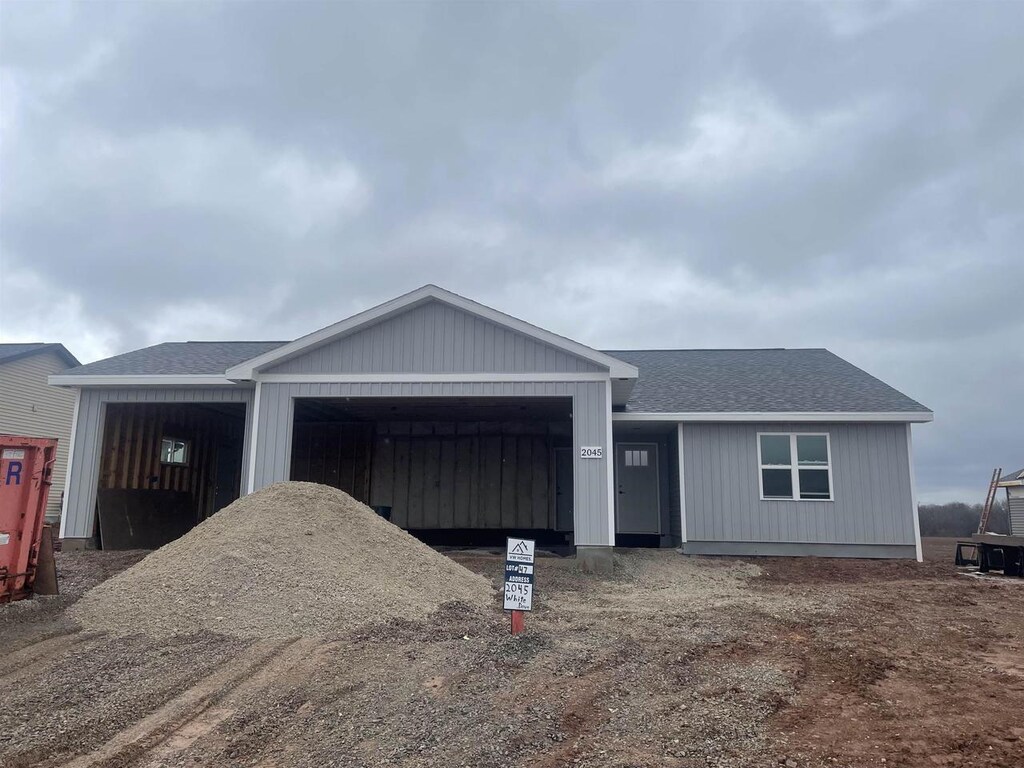 ranch-style house with driveway, roof with shingles, and a garage