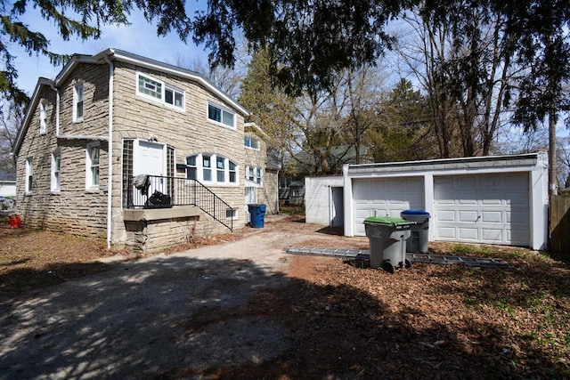 exterior space with a garage, an outbuilding, and stone siding