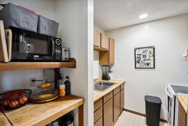 kitchen with recessed lighting, white range with electric stovetop, a sink, baseboards, and a textured ceiling