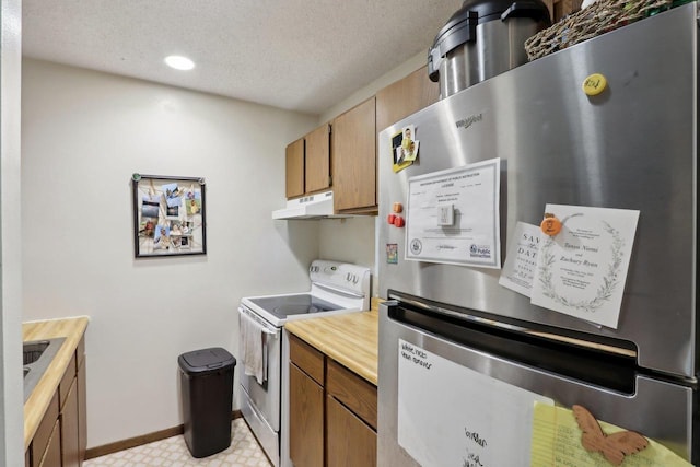 kitchen with freestanding refrigerator, electric range, light countertops, brown cabinets, and a textured ceiling
