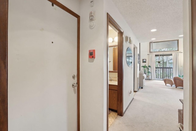 hall featuring recessed lighting, a textured ceiling, and light colored carpet