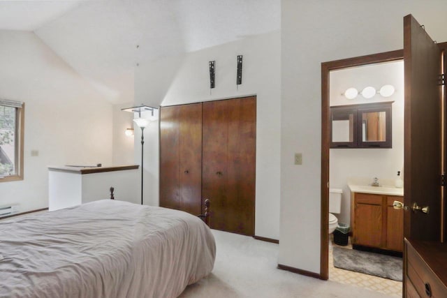 bedroom featuring a closet, vaulted ceiling, light carpet, a sink, and baseboards