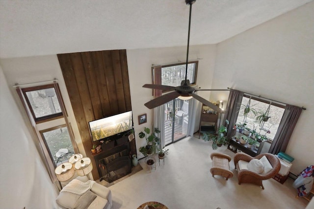 living area featuring a ceiling fan, a high ceiling, and a fireplace