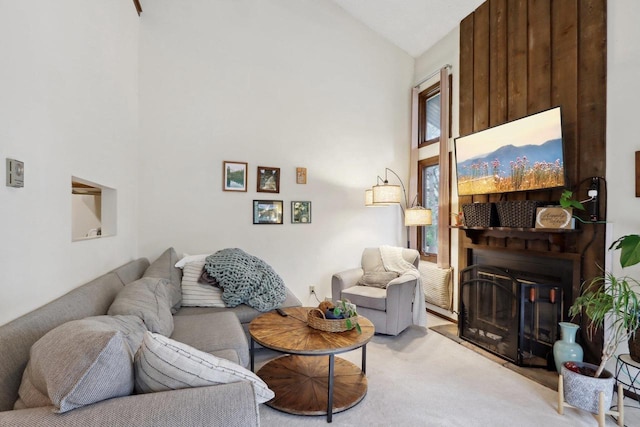 living room with high vaulted ceiling, light carpet, and a glass covered fireplace
