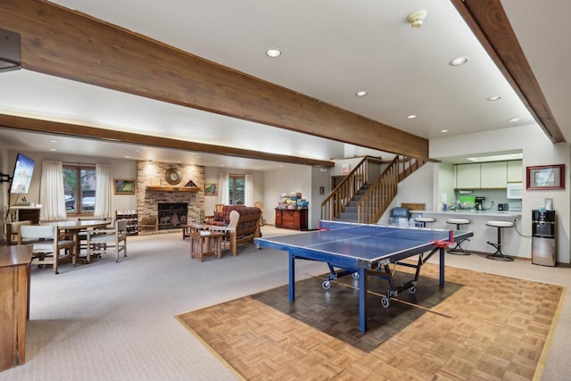 rec room featuring recessed lighting, beamed ceiling, a fireplace, and plenty of natural light