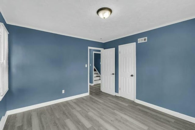unfurnished bedroom featuring wood finished floors, visible vents, a closet, and baseboards