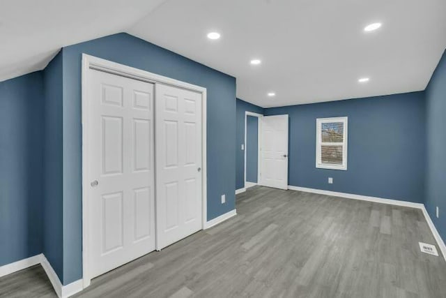 unfurnished bedroom featuring wood finished floors, a closet, and baseboards