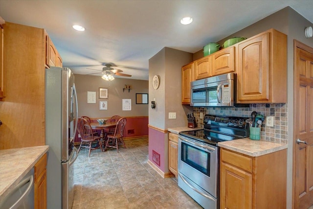 kitchen featuring decorative backsplash, baseboards, ceiling fan, light countertops, and appliances with stainless steel finishes