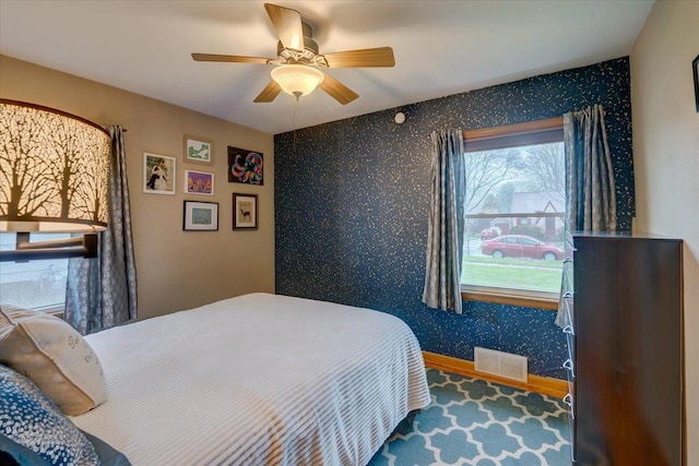 bedroom featuring baseboards, a ceiling fan, wallpapered walls, and visible vents