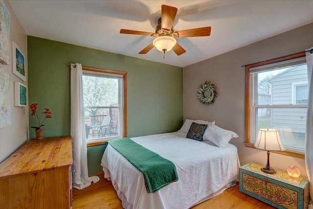 bedroom with a ceiling fan, light wood finished floors, and multiple windows