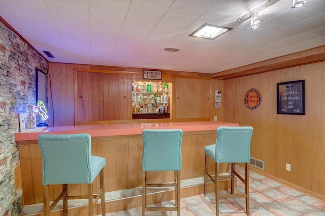bar featuring wooden walls, visible vents, and a dry bar