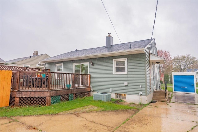 back of property featuring cooling unit, a wooden deck, and a chimney