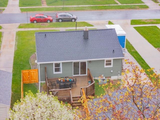 back of house with roof with shingles, a chimney, a lawn, and a deck
