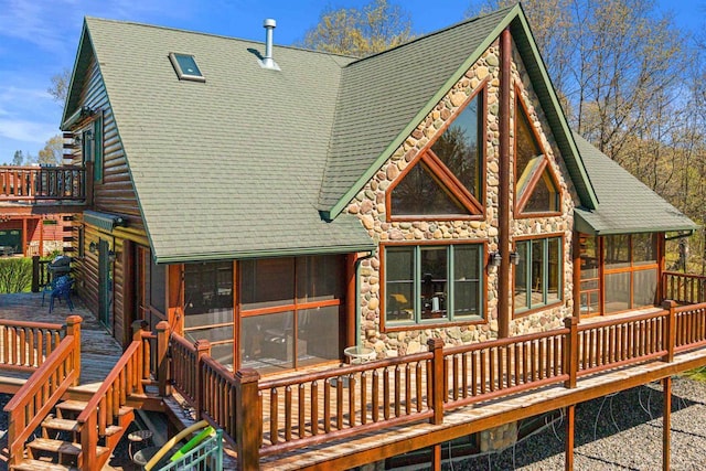 W4895 Big Bay Rd, Necedah, WI 54646 - back of property with a sunroom, roof with shingles, stone siding, and a wooden deck
