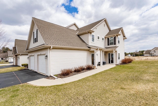 view of home's exterior with a lawn, roof with shingles, aphalt driveway, and an attached garage