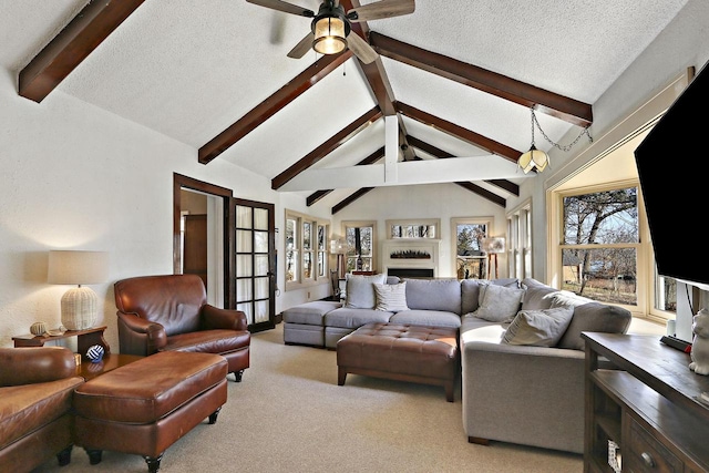 living area with a fireplace, ceiling fan, vaulted ceiling with beams, light colored carpet, and a textured ceiling
