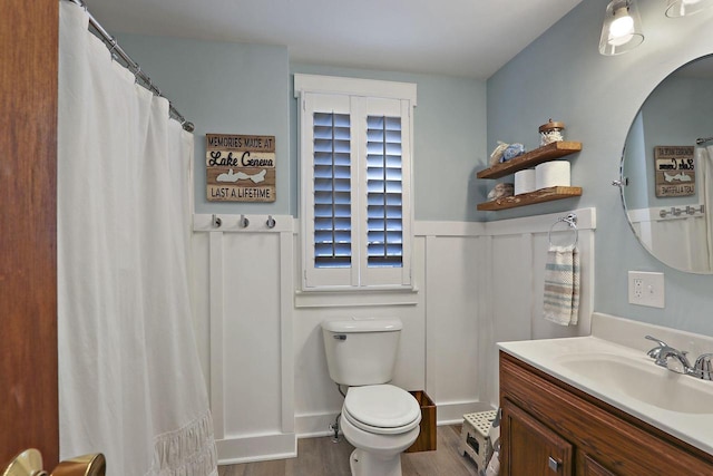 full bath featuring toilet, wainscoting, wood finished floors, and vanity