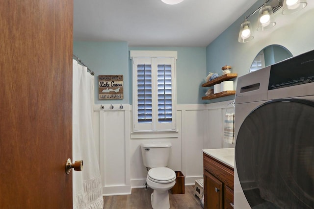 full bathroom featuring washer / clothes dryer, wood finished floors, a wainscoted wall, vanity, and toilet