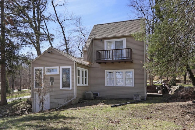 rear view of house featuring roof with shingles, central AC, and a balcony