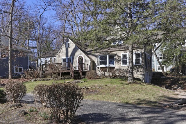 view of side of home with stairs, a wooden deck, and a yard