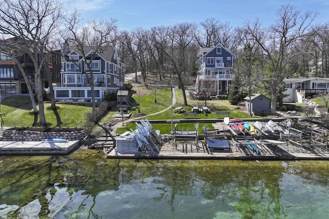 view of dock featuring a water view, a yard, and a balcony