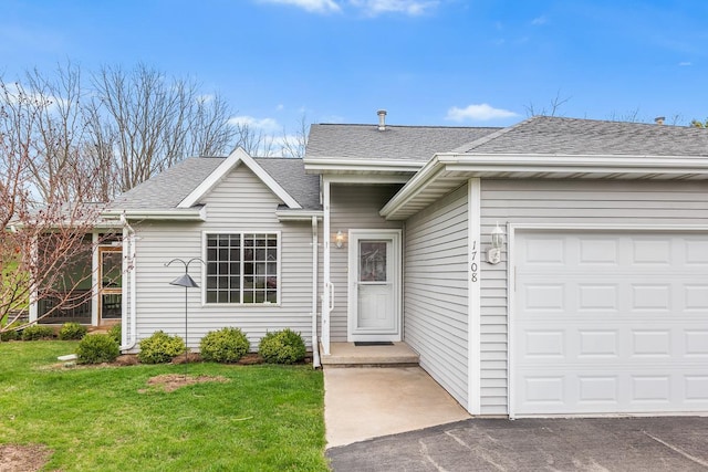 ranch-style house featuring a front yard, an attached garage, and roof with shingles